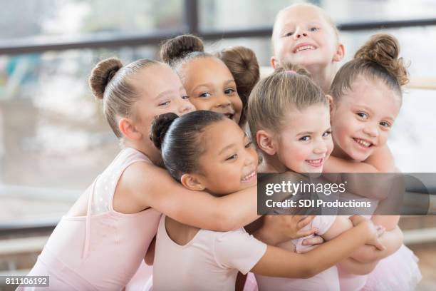 jonge ballerina's vormen een lachende groep knuffel - balletdanser stockfoto's en -beelden