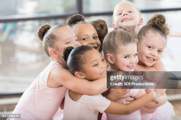 young ballerinas form a smiling group hug - dance studio stock pictures, royalty-free photos & images