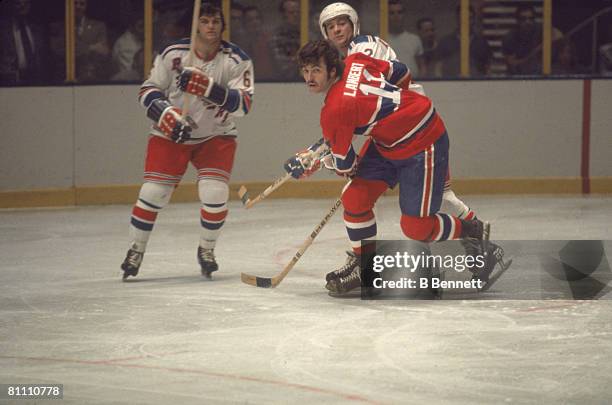 Canadian ice hockey player Yvon Lambert of the Montreal Canadiens, flanked by a pair of New York Rangers during a game, 1970s.