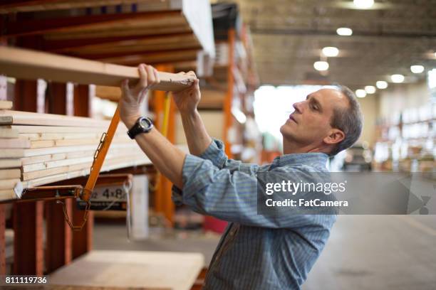 adult male customer in hardware store choosing lumber - hardware shop stock pictures, royalty-free photos & images