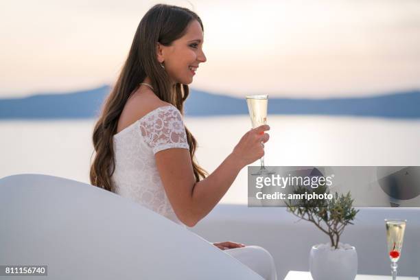 jonge vrouw in trouwjurk met glas mousserende wijn - santorini wedding stockfoto's en -beelden