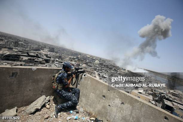 An Iraqi forces sniper looks on as smoke billows, following an airstrike by US-led international coalition forces targeting Islamic State group, in...
