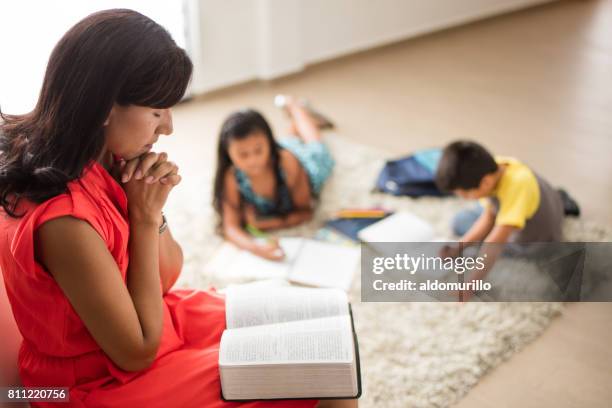 latin mother sitting with bible and praying - child praying stock pictures, royalty-free photos & images