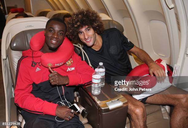 Eric Bailly and Marouane Fellaini of Manchester United sit on the aeroplane ahead of the club's pre-season tour of the USA at Manchester Airport on...