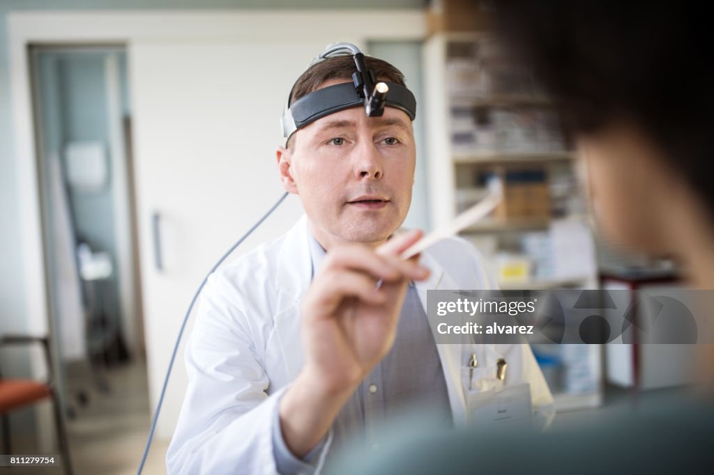 Homme médecin examinant la gorge du patient féminin