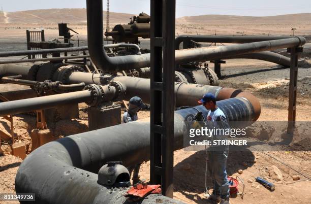 Picture taken on July 9, 2017 shows workers at Syria's Arak gas field, 35 kilometres northeast of the ancient city of Palmyra, in the central...