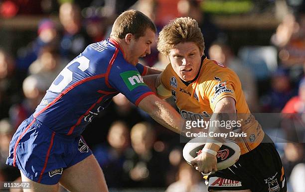 Chris Lawrence of the Tigers is tackled by Scott Dureau of the Knights during the round 10 NRL match between the Newcastle Knights and the Wests...