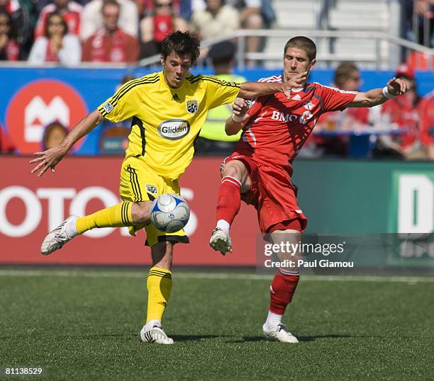 Toronto FC midfielder Carl Robinson kicks for the ball with Columbus Crew midfielder Brad Evans during their game on May 17, 2008 at BMO Field in...