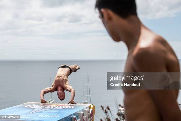 In this handout image provided by Red Bull, Artem Silchenko of Russia dives from the 27 metre platform while Sergio Guzman of Mexico watches on at...
