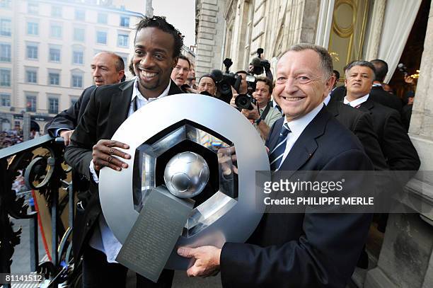 Lyon's L1 football French forward Sidney Govou and president Jean-Michel Aulas hold the trophy on the balcony of City Hall in front of team...