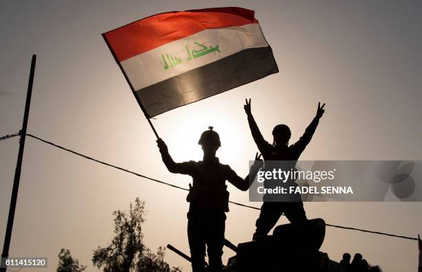 Iraq's federal police members wave Iraq's national flag as they celebrate in the Old City of Mosul on July 9, 2017 after the government's...