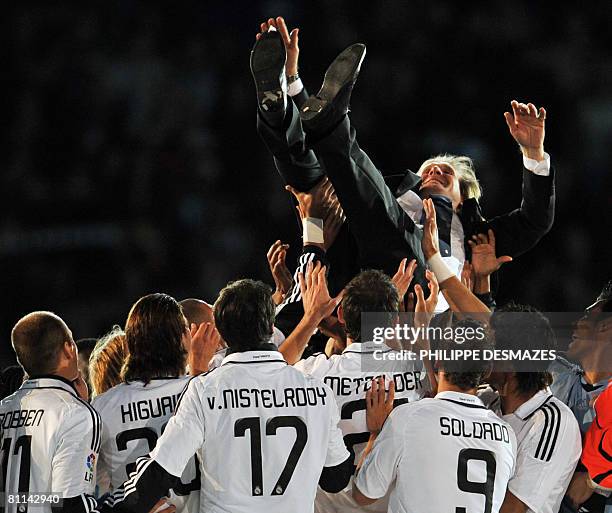 Real Madrid's German coach Bernd Schuster is thrown in the air after Real won the Spanish league title at the Santiago Bernabeu stadium in Madrid, on...