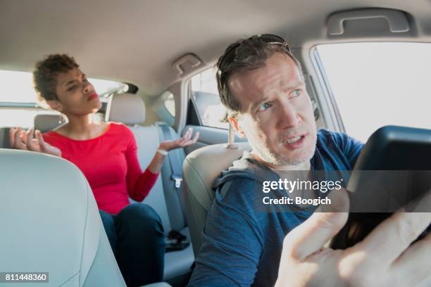 angry millennial passenger complaining to lost driver with mobile phone - uber driver stock pictures, royalty-free photos & images