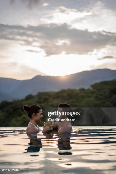 happy couple on holidays having drinks at the pool - happy holidays around the world stock pictures, royalty-free photos & images
