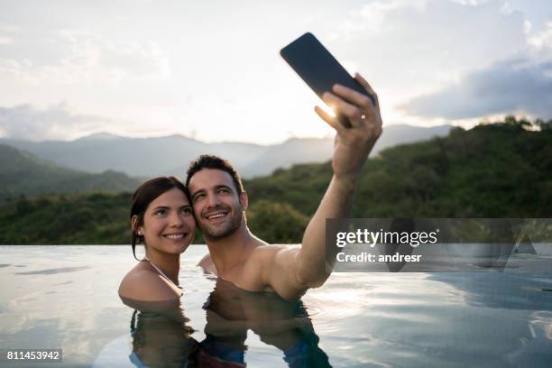 couple on vacations taking a selfie in the pool - social class stock pictures, royalty-free photos & images