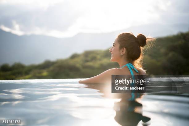 schöne frau entspannen am pool - infinity pool stock-fotos und bilder