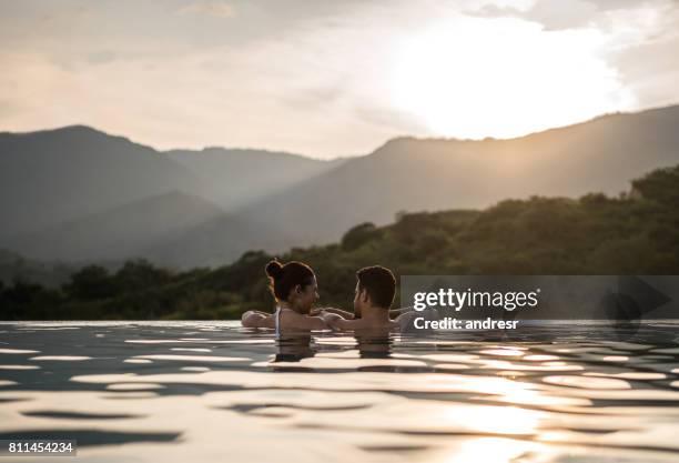 romantic couple watching the sunset in the swimming - honeymoon stock pictures, royalty-free photos & images