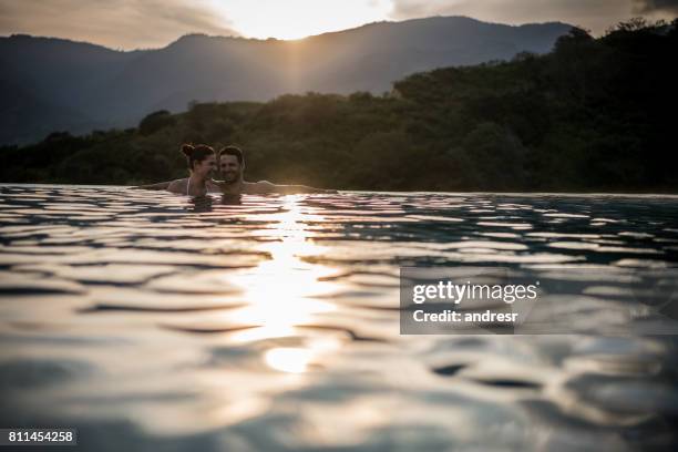 couple enjoying their summer holidays and looking happy in the pool - happy holidays around the world stock pictures, royalty-free photos & images