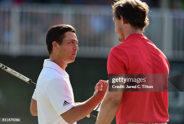 Xander Schauffele shakes hands with Jamie Lovemark after his birdie putt on the 18th green to take the outright lead during the final round of The...