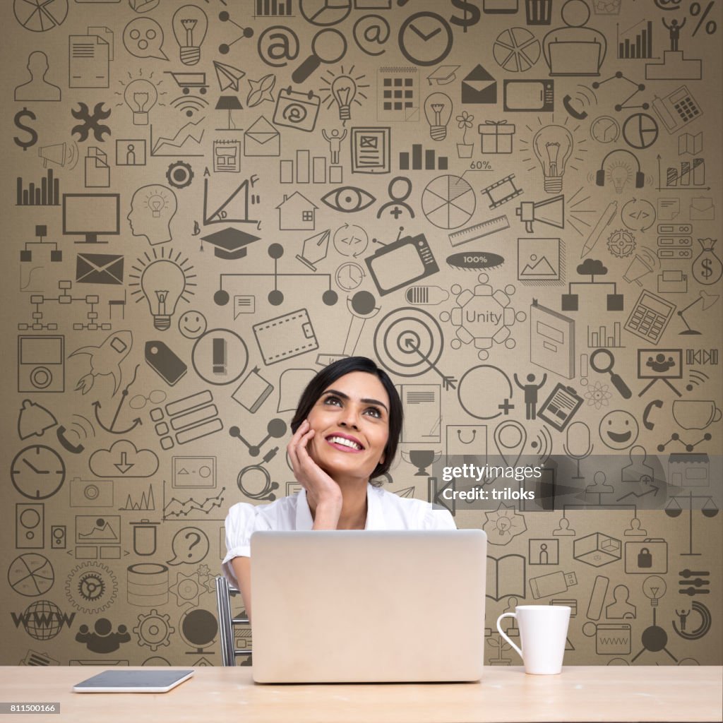 Thoughtful businesswoman with laptop at office desk