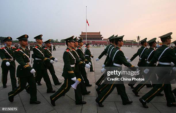Paramilitary policemen walk on the Tiananmen Square, where the Chinese national flag flies at half-mast, as China begins three days of national...