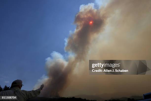 Smoke obscures the sun as a U.S. Forest Service official watches the Whittier Fire burn towards SR-154 in the Los Padres National Forest near Lake...