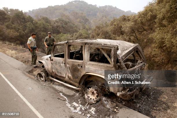 Santa Barbara deputy Sheriff B. Bruening, left, and U.S. Fish & Wildlife game warden Max Magleby view a jeep that was abandoned and scorched by the...