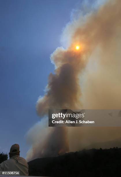 Smoke obscures the sun as a U.S. Forest Service official watches the Whittier Fire burn towards SR-154 in the Los Padres National Forest near Lake...