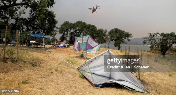 Fire-figging helicopter passes by as tents, food and personal belongs remain abandoned after campers were evacuated from the fast-moving Whittier...