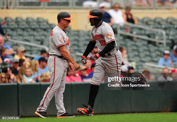 Baltimore Orioles Center field Adam Jones high-fives third base coach Bobby Dickerson after hitting a three-run home run against the Minnesota Twins...