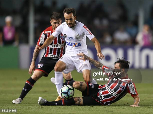 Thiago Ribeiro of Santos battles for the ball with Jonathan Gomez and Buffarini of Sao Paulo during the match between Santos and Sao Paulo as a part...