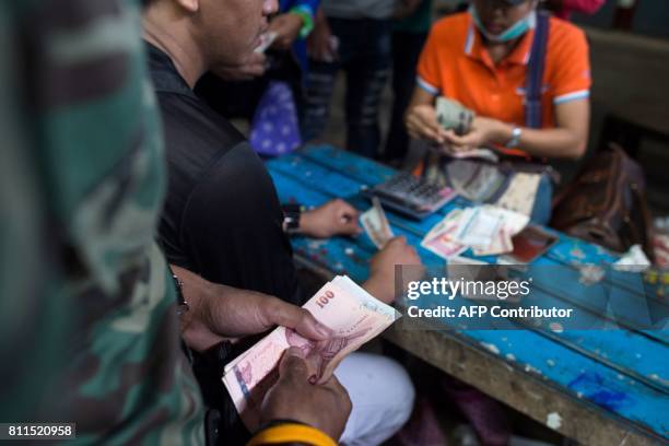 This photo taken on July 6, 2017 shows migrant workers changing money from Thai baht to Myanmar kyat at the Myanmar imigration office in Myawaddy....