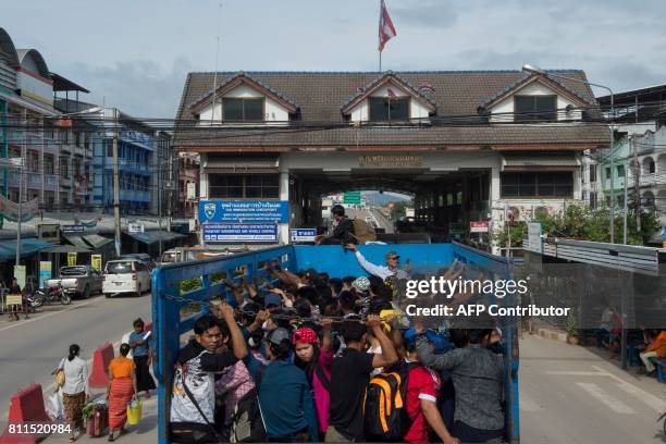 This photo taken on July 7, 2017 shows migrant workers passing the Thai-Myanmar border in an official service truck as they leave Thailand in Mae...