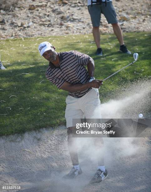 Broadcaster and former professional basketball player Eddie Johnson hits a sand bunker shot during the Coach Woodson Las Vegas Invitational at...