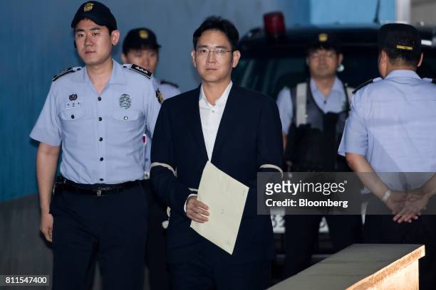 Jay Y. Lee, co-vice chairman of Samsung Electronics Co., center, is escorted by a prison officer as he arrives at the Seoul Central District Court in...
