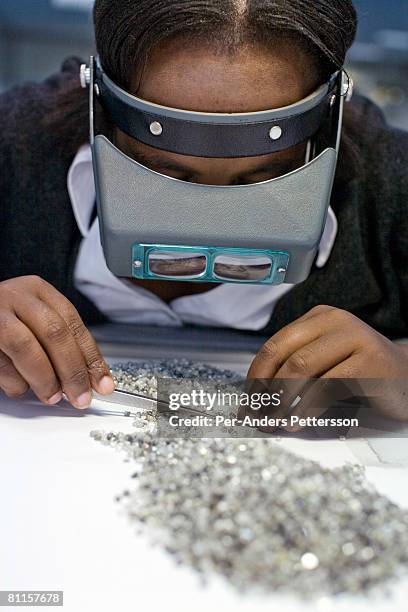 An unidentified woman sorts raw diamonds as they are displayed on tables at the new Diamond Trading Company , the world's largest and most advanced...