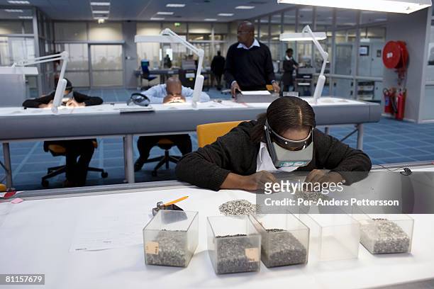 An unidentified woman sorts raw diamonds as they are displayed on tables at the new Diamond Trading Company , the world's largest and most advanced...
