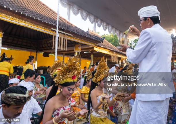 Priest blessing with water some teenagers in traditional costumes before a tooth filing ceremony, Bali island, Canggu, Indonesia on July 22, 2015 in...