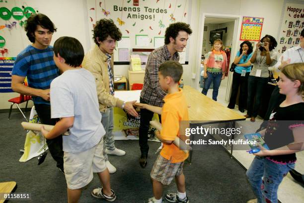 Joe Jonas, Nick Jonas and Kevin Jonas of The Jonas Brothers greet students as part of the Topps Baby Bottle Pop School Concert Invasion for students...