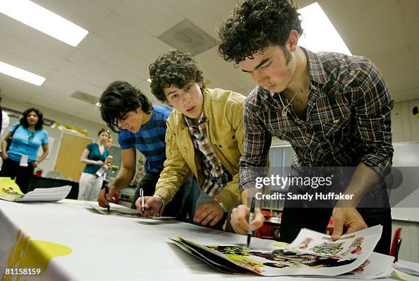 Joe Jonas, Nick Jonas and Kevin Jonas of The Jonas Brothers sign autographs as part of the Topps Baby Bottle Pop School Concert Invasion for students...