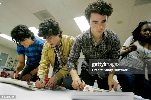 Joe Jonas, Nick Jonas and Kevin Jonas of The Jonas Brothers sign autographs as part of the Topps Baby Bottle Pop School Concert Invasion for students...
