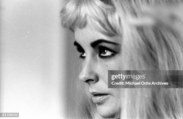 Actress Elizabeth Taylor poses for a portrait session wearing a blonde wig while fixing her make up and hair in 1963.