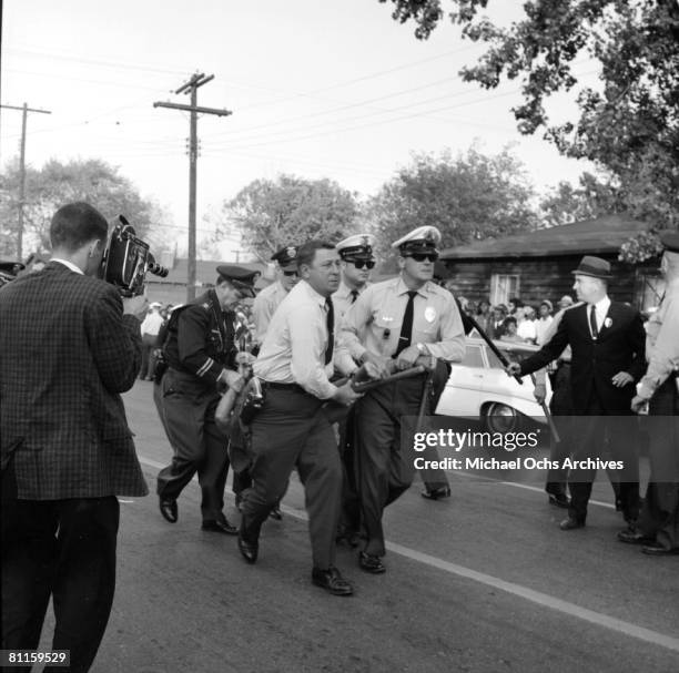 An African American woman is dragged away by policemen during a protest against segregation organized by Reverend Dr. Martin Luther King Jr. And...