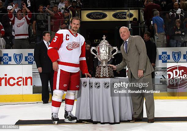 Defenseman Nicklas Lidstrom of the Detroit Red Wings stands next to the Clarence S. Campbell Bowl with Bill Daly, deputy commisioner of the NHL after...