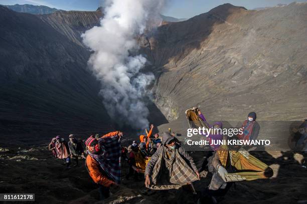 Indonesian villagers catch money and live offerings thrown by members of the Tengger tribe into the crater of mount Bromo volcano during the Yadnya...