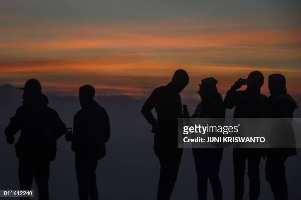 Indonesian tourists wait for members of the Tengger tribe as the sun rises at mount Bromo volcano during the Yadnya Kasada Festival in Probolinggo on...