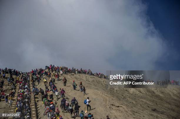 Tourists and members of the Tengger tribe climb mount Bromo during the Yadnya Kasada Festival in Probolinggo on July 10, 2017. Members of the Tengger...