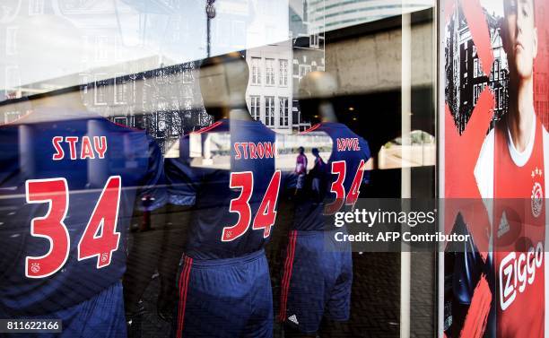 Picture taken through a shop window show football jerseys bearing the words 'Stay Strong Appie' and the number 34 to show support to Ajax midfielder...
