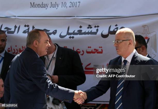 Palestinian prime minister Rami Hamdallah shakes hands with Israeli Energy Minister Yuval Steinitz on July 10 as they attend a ceremony in Jalamah,...
