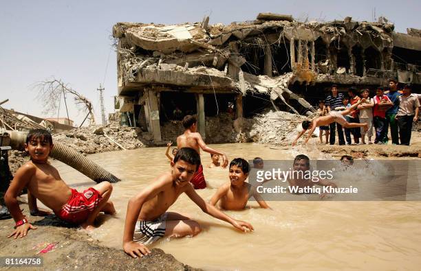 Iraqi boys swim in a pond caused by an explosion from recent fighting on May 20, 2008 in the Shiite district of Sadr City in Baghdad, Iraq. Iraqi...